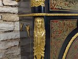 a black and gold cabinet with a clock on top of it