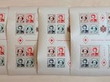 quatre timbres différents représentant des personnes, posés sur une feuille de papier posée sur une table