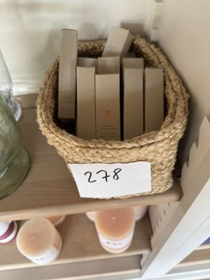 un panier rempli de livres posé sur une étagère, à côté d'un bocal contenant des bougies