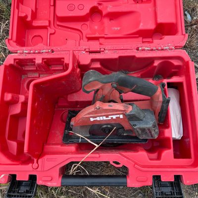 une boîte à outils rouge contenant des outils, posée par terre