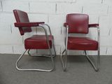 two red chairs sitting next to each other in front of a white brick wall