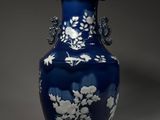 un vase bleu orné de fleurs blanches, posé sur une table