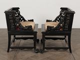pair of antique black chairs with upholstered cushions on a herringy wood floor