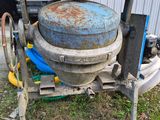 a cement mixer sitting in the grass next to a building
