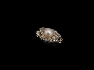 un gros plan d'une broche en perles et diamants sur fond noir