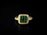 a close up of a ring with a green stone surrounded by white diamonds