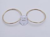 two gold rings with a tag attached to them on a white surface