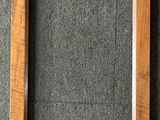 un cadre en bois vide posé sur un tapis gris