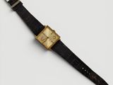 gros plan d'une montre sur une surface blanche avec un bracelet noir
