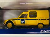 une ambulance jouet jaune à rayures bleues et blanches, dans une boîte blanche