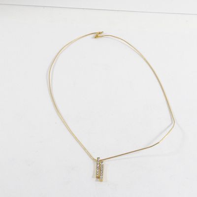 un collier en or avec un pendentif en forme de barre sur un fond blanc