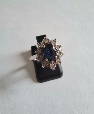 gros plan d'une bague avec une pierre bleue entourée de diamants blancs