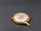 a gold watch sitting on a black surface