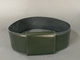 green leather belt with a metal buckle on a gray surface