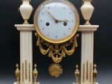 a white and gold clock on a stand on a black background