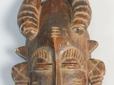 une image représentant un masque en bois muni de cornes sur fond blanc