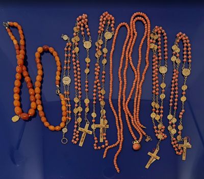 Plusieurs perles et croix orange sont disposées sur un fond bleu
