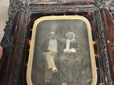 Quelqu'un tient une photo encadrée représentant un homme et une femme.