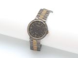 une montre-bracelet argentée et dorée posée sur une surface blanche