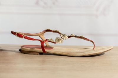 La femme porte une paire de sandales rouges posées sur une table en bois.