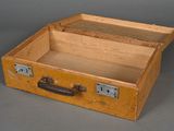 a small wooden suitcase with a handle on a gray surface