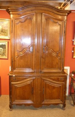 une grande armoire en bois dans une pièce où sont accrochés des tableaux aux murs