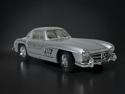 a silver toy car that is sitting on a black surface