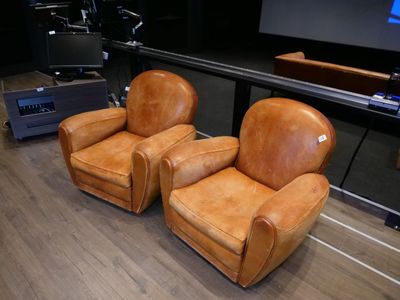 deux fauteuils en cuir marron placés devant un écran de projection