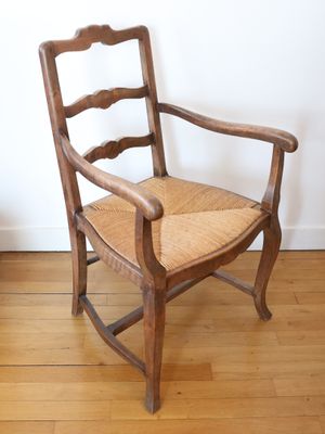 a wooden chair with a woven seat on a hard wood floor
