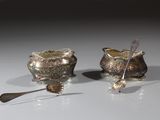 two silver spoons and a silver bowl on a table