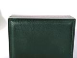 un portefeuille vert posé sur une surface blanche à côté d'une lampe