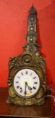 une horloge posée sur une table devant un mur rouge