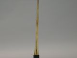 a small wooden sword on a metal stand on a white surface