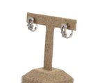 pair of silver earrings on a stand against a white background