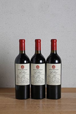 three bottles of wine sitting on a wooden table next to a clock