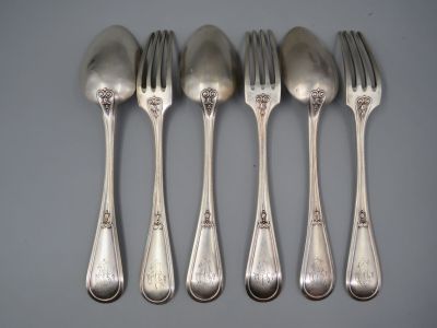 quatre cuillères en argent et une fourchette posées sur un plan de travail gris