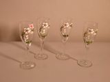 four wine glasses with flowers painted on them on a table