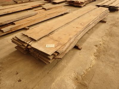 Plusieurs morceaux de bois sont empilés sur le sol d'un entrepôt