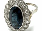 a close up of a ring with a blue stone surrounded by diamonds