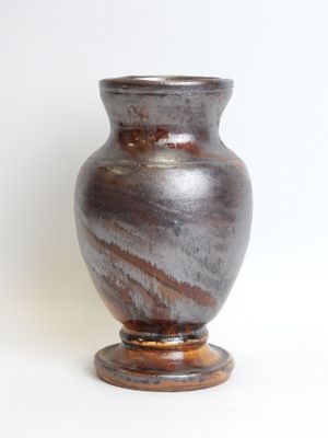 a brown vase sitting on top of a white table