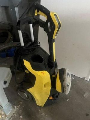un nettoyeur haute pression jaune et noir posé à côté d'une poubelle