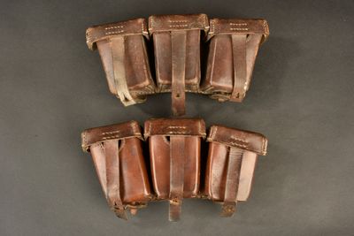four leather holsters are lined up on a gray surface