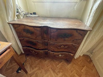 une commode dans un coin d'une pièce où se trouve une fenêtre
