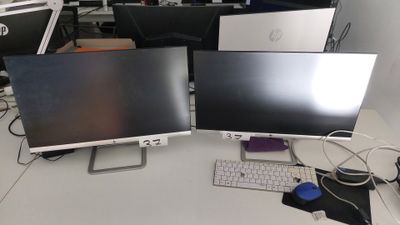 trois écrans d'ordinateur posés sur un bureau, avec un clavier et une souris