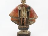 an old wooden statue of a man with a cape on a white background