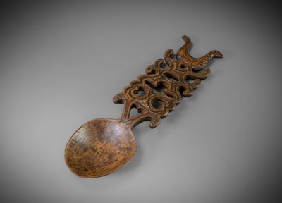 a close up of a wooden spoon with a carved handle