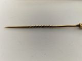 a close up of a gold hair pin on a white surface