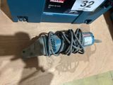 a corded drill on the floor next to a blue box