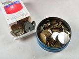 a tin of coins sitting on a table next to a box of coins