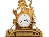une horloge en or avec une femme assise dessus